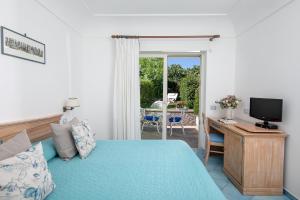 a bedroom with a bed and a desk with a television at Hotel Al Mulino in Anacapri