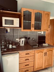 a kitchen with wooden cabinets and a sink and a microwave at Celtis Lane Guest House in Boksburg