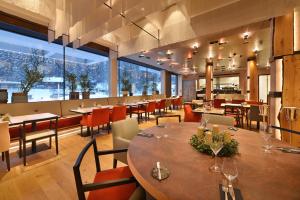 um restaurante com mesas e cadeiras e janelas grandes em Grand Hotel Hradec em Pec pod Sněžkou