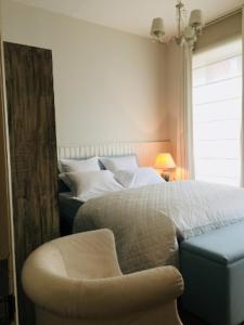 1 dormitorio con 1 cama y 1 silla junto a una ventana en Kirisavan Bed&Breakfast, en Borgloon