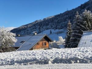 una cabaña de madera en la nieve con un panel solar en AlpinResort Kaprun 2 en Kaprun