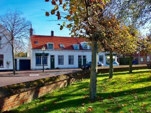 a large white house with a red roof at Vakantiehuis Dorpsplein in Koudekerke