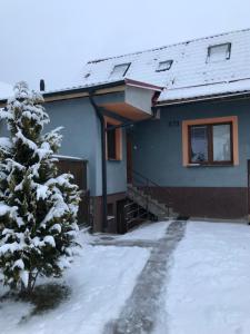 Una casa en la nieve con un árbol de Navidad en POD CHOČOM, en Lúčky