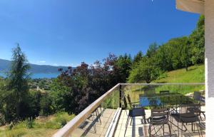 a balcony of a house with a table and chairs at Vue exceptionnelle sur lac d'Annecy et Montagnes in Menthon-Saint-Bernard