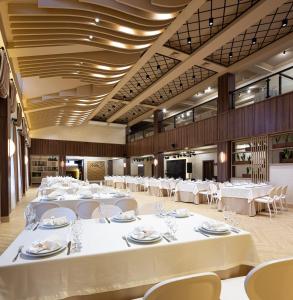 una grande sala banchetti con tavoli e sedie bianchi di NeboS Hotel & Restaurant a Ivano-Frankivsʼk