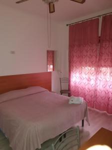 a bedroom with a bed and a pink curtain at Albergo Anna in Ciampino