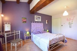 a bedroom with a bed and a purple wall at Villa charmante à Saint-Didier avec piscine privée in Saint-Didier