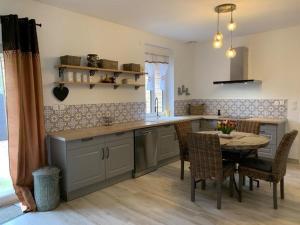 a kitchen with a table and a table and chairs at La grange du bois in Fresnicourt-le-Dolmen +19 photos