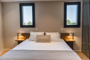 een slaapkamer met een groot wit bed en 2 ramen bij Alinea Suites Limassol Center in Limassol