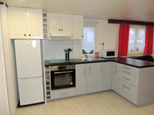 uma cozinha com armários brancos, um lavatório e um frigorífico em Mobil Home Fradin Parc de loisirs em Talmont
