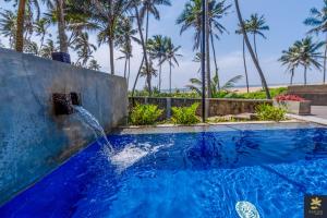 a swimming pool with a water fountain at Rakuen Beach Villa in Hikkaduwa