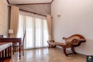 a living room with a bench and a large window at Rakuen Beach Villa in Hikkaduwa