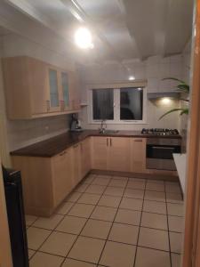 a kitchen with wooden cabinets and a tile floor at Khaki Campbell in Ermelo