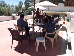 a group of people sitting around a table on a patio at Smanla guest house in Leh