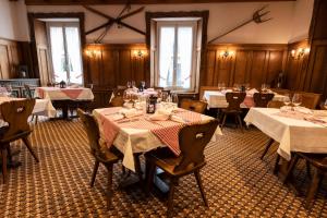 uma sala de jantar com mesas e cadeiras com toalhas de mesa brancas em Hotel Schweizerhof em Engelberg