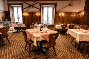a dining room with tables and chairs with white tablecloths at Hotel Schweizerhof in Engelberg