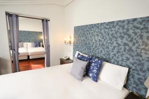 um quarto com uma grande cama branca com almofadas azuis em Hotel Conde Rodrigo 2 em Ciudad-Rodrigo