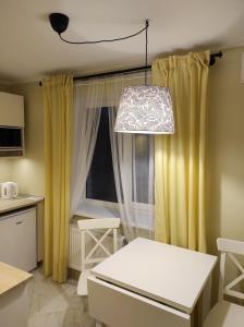 a kitchen with yellow curtains and a chandelier at Apartment Paula in Saldus