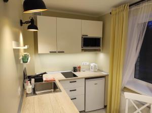 uma pequena cozinha com armários brancos e uma janela em Apartment Paula em Saldus
