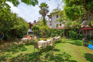 a garden with tables and chairs in front of a house at Villa Partheniou & Garden in Sivota