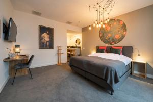 a bedroom with a bed and a desk and a chandelier at Boutique hotel & brasserie de Heerlyckheid in Bredevoort