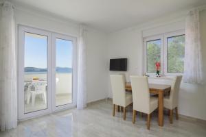 a dining room with a table and chairs and windows at Villa Anđelo in Trogir