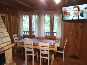 ein Esszimmer mit einem Tisch und Stühlen sowie einem TV in der Unterkunft Warchały near Szczytno, RUSTIC LODGE at Lake in Narty