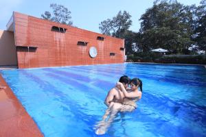 Zwei Leute umarmen sich in einem Pool in der Unterkunft Aveo by Amatra, Gateway to Corbett in Kāshīpur