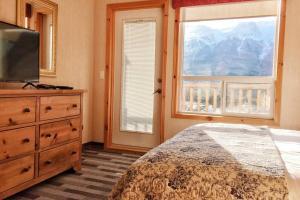 a bedroom with a bed and a television and a window at MountainView -PrivateChalet Sleep7- 5min to DT Vacation Home in Canmore