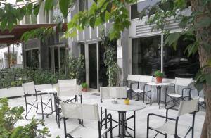 a patio with white chairs and tables in front of a building at Rex Chasioti in Loutra Ipatis +9 photos