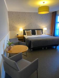 Cette chambre d'hôtel comprend deux lits, une table et des chaises. dans l'établissement Hotel Hof van 's Gravenmoer, à 's-Gravenmoer