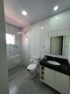 a bathroom with a toilet and a sink and a mirror at Hotel Carmelo in São José dos Pinhais