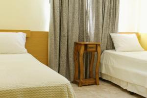 a room with two beds and a night stand next to a window at Volver a Casa in Corrientes