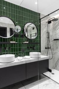 a bathroom with two sinks and a green tiled wall at A22 Hotel in Rīga
