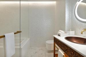 Hotel Indigo Dubai Downtown, an IHG Hotel في دبي: حمام مع حوض ومرحاض ومرآة