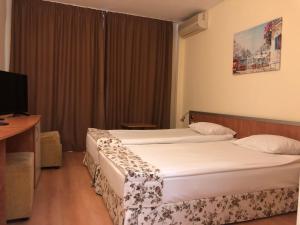 a hotel room with two beds and a television at Hotel Atol in Sunny Beach