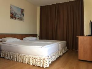 a bedroom with a large white bed and a television at Hotel Atol in Sunny Beach