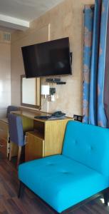 ein Wohnzimmer mit einem blauen Sofa und einem Schreibtisch in der Unterkunft Studiotel Afoud in Agadir