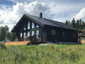 ein großes schwarzes Haus mit einer großen Terrasse in der Unterkunft Jarvso House. Ski In / Ski Out. in Järvsö