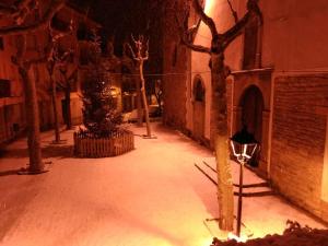 a snow covered alley with trees and a building at Escloper B&B in Sant Juliá de Vilatorta