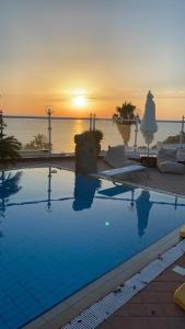a swimming pool with a sunset over the ocean at Dimorra Sun and Relax in Ischia