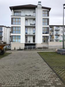 a white apartment building with a brick driveway at Apartment Yanina SŁONECZNE TARASY in Dziwnówek