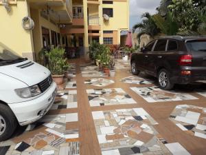 twee auto's geparkeerd op een parkeerplaats met mozaïekvloeren bij Afilux Residencial in Luanda