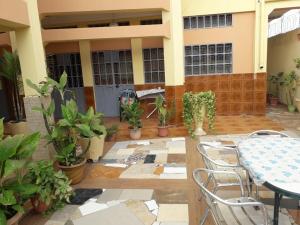 um pátio com uma mesa, cadeiras e vasos de plantas em Afilux Residencial em Luanda