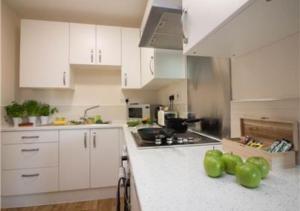 a kitchen with white cabinets and green peppers on the counter at StayZo Castle Point 18 Apartments - Premier Lodge in Southampton