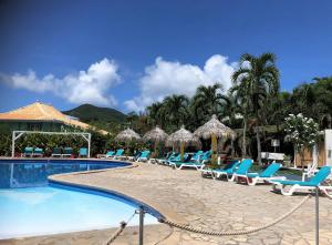 una piscina con sedie a sdraio e un resort di Le Mayann a Le Diamant