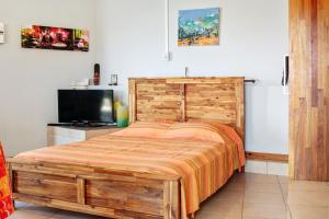 sypialnia z drewnianym łóżkiem i telewizorem w obiekcie Studio avec vue sur la mer jardin clos et wifi a L'etang sale a 6 km de la plage w mieście Étang-Salé