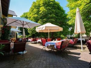 eine Terrasse mit Tischen, Stühlen und Sonnenschirmen in der Unterkunft Gasthaus Poelt in Feldafing