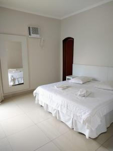 a white bedroom with a bed and a mirror at Hotel Alzira Imperial in São Lourenço