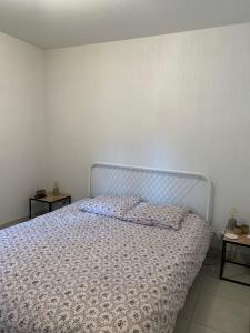 a bed in a bedroom with a white wall at Appartement cosy Briançon in Briançon